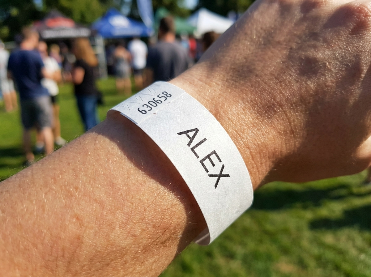 Bracelet Tyvek blanc imprimé avec le prénom d'un enfant et un numéro de téléphone d'urgence, porté au poignet d'un jeune enfant lors d'un événement en plein air